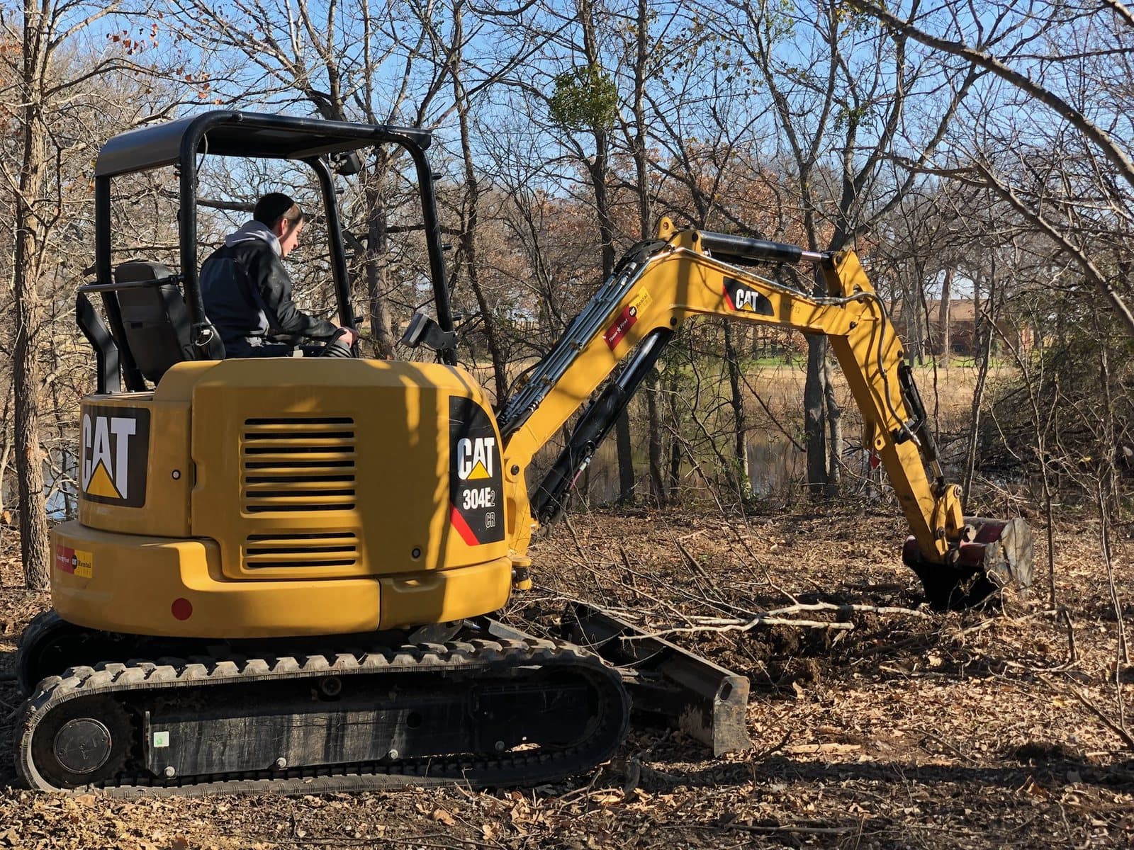 Excavator working on a wooded plumbing service site