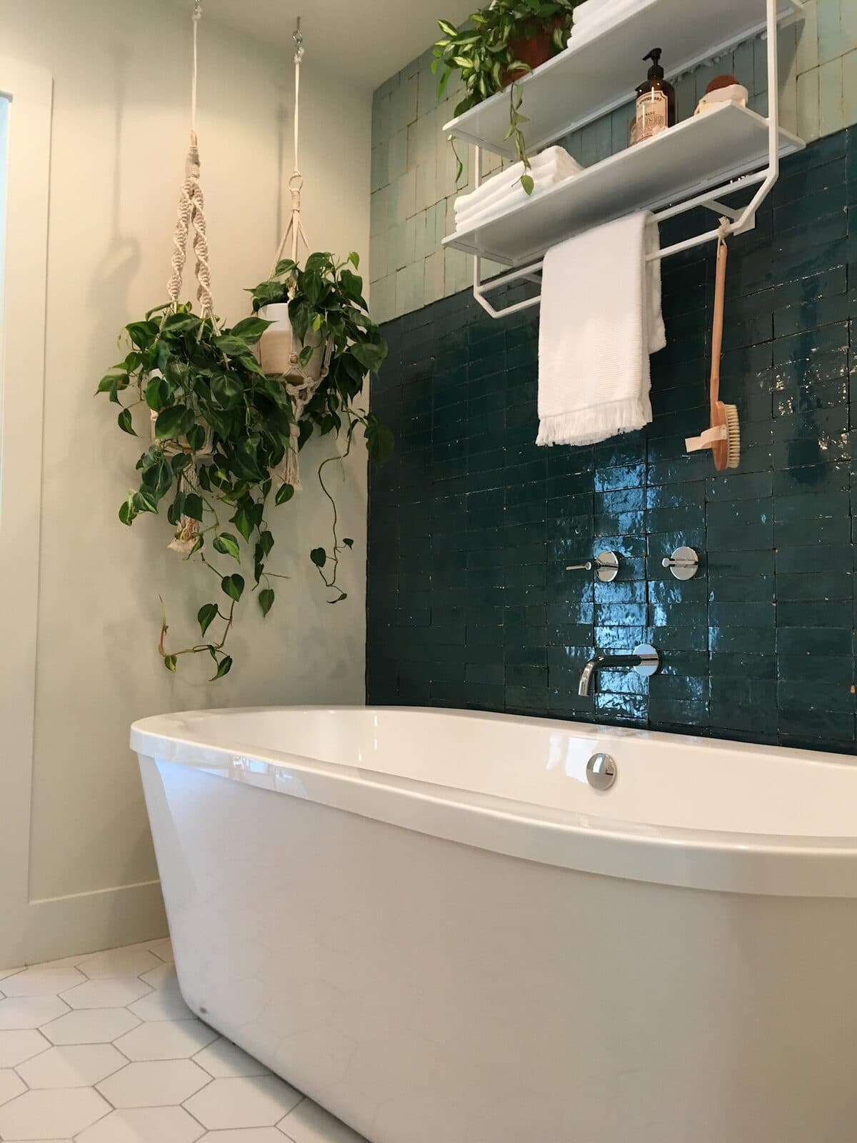 Freestanding soaking tub against a tiled feature wall in a finished bathroom remodel
